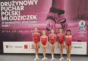 Zawodniczki stoją przed plakatem zawodów