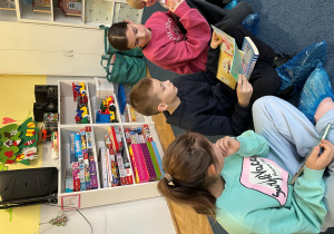 Uczniowie siedzą na dywanie