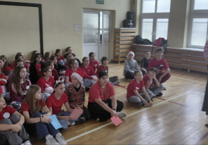 Uczniowie siedzą na sali gimnastycznej