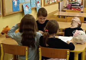 Dzieci współpracują ze sobą w ławce wykonując zadanie plastyczne