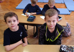 Uczniowie siedzą w ławce