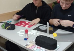 Chłopcy siedzą przy stoliku i pracują