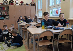 Uczniowie zastanawiają się porzy stoliku jak można pomóc osobie niepełnosprawnej