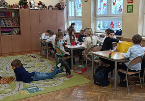 Dzieci myślą przy stolikach nad ćwiczeniem na kreatywnosć