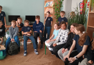 Uczniowie siedzą na krzesełkach