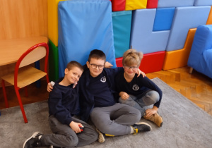 Uczniowie siedzą na dywanie