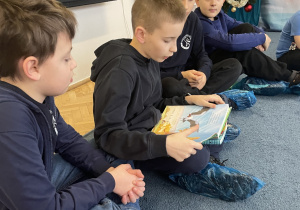 Uczniowie siedzą na dywanie