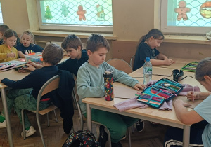 Dzieci rysują przy stolikach portret babci