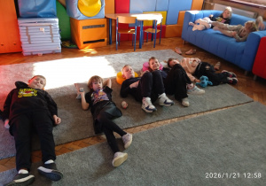Uczniowie odpoczywają na dywanie
