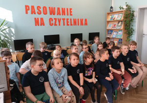 Uczniowie siedzą na krzesełkach