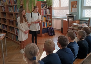 Uczniowie siedzą na krzesełkach