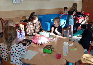 Dzieci tworzą przy stoliku portret dziadka