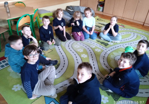 Uczniowie siedzą w kręgu na dywanie