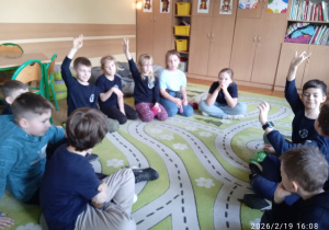 Uczniowie siedzą na dywanie