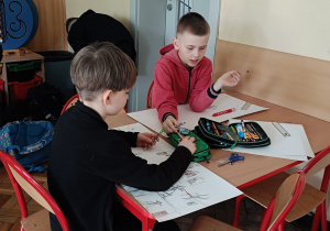Uczniowie wspólnie rysują przy stoliku