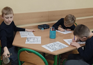 Dzieci wykonują ćwiczenie plastyczne przy stoliku