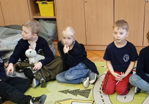 Uczniowie siedzą na dywanie