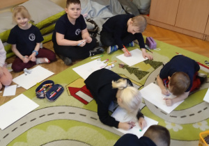 Uczniowie rysują na dywanie