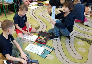 Dzieci kolorują obrazek z dinozaurem