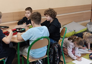 Dzieci współpracują ze sobą przy wykonywaniu pracy plastycznej