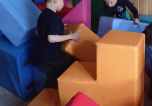 Uczniowie budują z dużych piankowych klocków