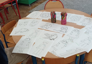 Uczeń siedzi przy stoliku z kolorowankami