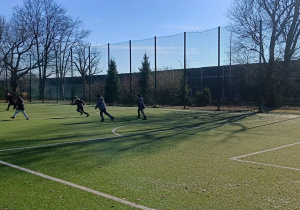 Chłopcy grają na boisku współpracując ze sobą