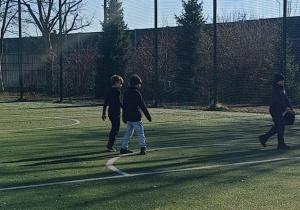 Dzieci biegają na boisku szkolnym grając w piłkę