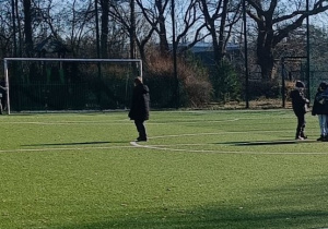 Uczniowie grają w piłkę na boisku