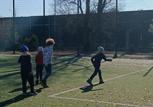 Uczniowie wykonują strzały do bramki ćwicząc wspólnie