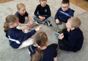 Uczniowie siedzą w kole