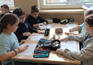 Dzieci pracują przy stolikach współpracując w grupie