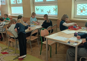 Dzieci wykonują ćwiczenie na myślenie kreatywne przy stolikach