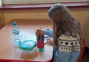 Uczennica pracuje przy stoliku podczas zajęć