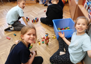 Uczniowie siedzą na podłodze