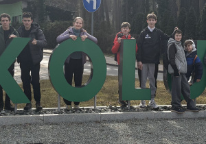 Grupa uczniów stoi przy napisie