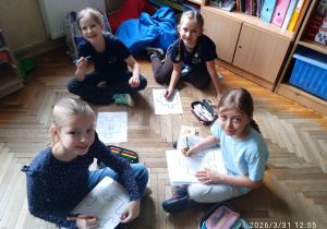 Uczniowie siedzą na podłodze