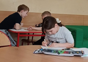 Dziewczynka wykonuje ćwiczenie przy stoliku