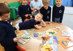 Uczniowie stoją wokół stołu z książkami