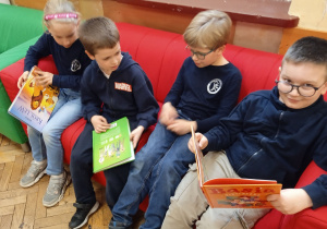 Uczniowie siedzą na kanapie i czytają