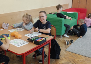 Dzieci pracują przy stoliku wykonując pracę plastyczną