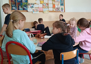 Uczniowie wykonują ćwiczenie plastyczne przy stoliku