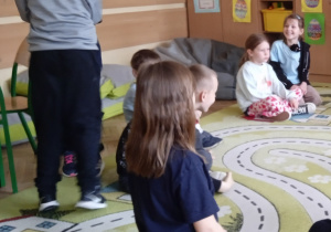 Uczniowie siedzą na dywanie