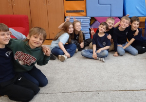 Uczniowie siedzą na dywanie