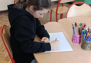 Dziewczynka wykonuje prace plastyczną na konkurs o Muminkach