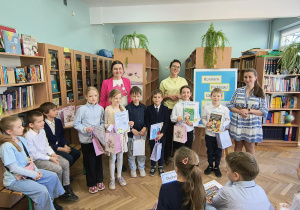 Uczniowie siedzą i stoją w bibliotece