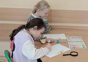 Dziewczynki rysują w ławce projekt książki z tytułem