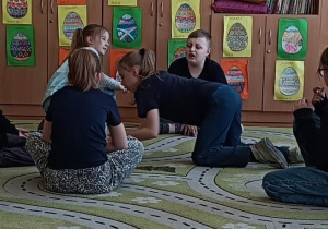 Dzieci w kręgu na dywanie wykonują ćwiczenie na kreatywność
