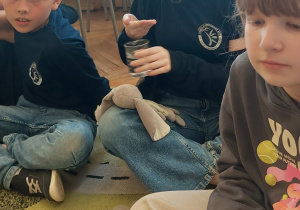 Uczniowie siedzą na dywanie