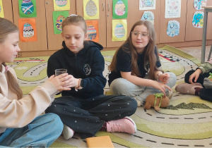 Uczennice siedzą na dywanie